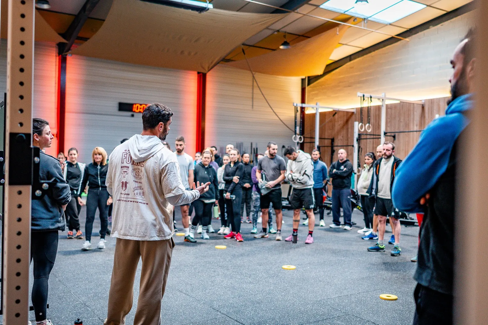 Un coach du Côtière Sport Club explique le WOD du jour à un groupe de membres réunis en cercle dans la box